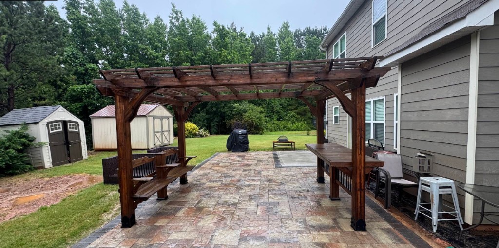 Backyard stone paver patio with a wooden pergola and outdoor seating after cleaning