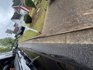 Residential street curb, sidewalk, and lawn with mailbox from a low street perspective